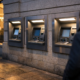 A row of European bank ATMs on a quiet city street at dusk