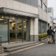 A regional bank branch facade in a Japanese city street, representing consolidation among Shikoku lenders
