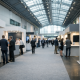 A modern trade fair hall in Frankfurt with exhibitor stands and visitors attending a finance expo