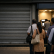 Closed shutters of an Indian bank branch with an ATM lobby beside the entrance