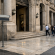 A bank facade in an Italian financial district with a directional street sign, symbolising a major Italian banking merger vote