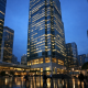 A corporate skyscraper facade in a major Asian financial district at dusk, representing a global bank's regional headquarters