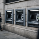 A row of ATMs on a London street with a cloudy sky, illustrating a UK banking outage